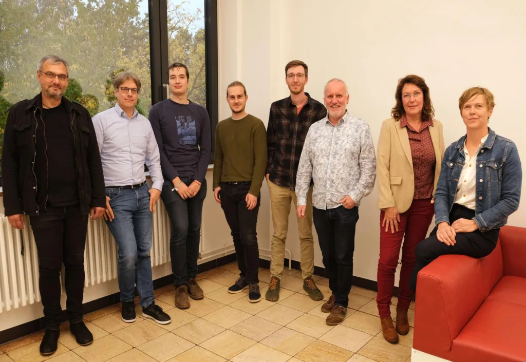 Teaching Advisory Board of Nordhausen University of Applied Sciences The members of the teaching advisory board are standing next to each other, with a woman sitting on the armrest of a red armchair on the far right.