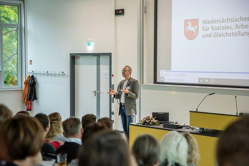 ein Mann auf dem Podium vor einer Video-Leinwand