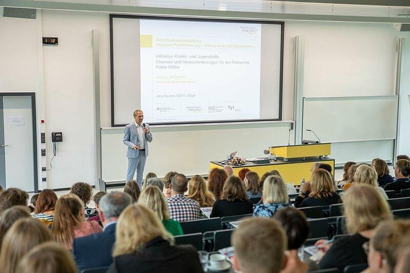 ein Mann auf dem Podium vor einer Video-Leinwand