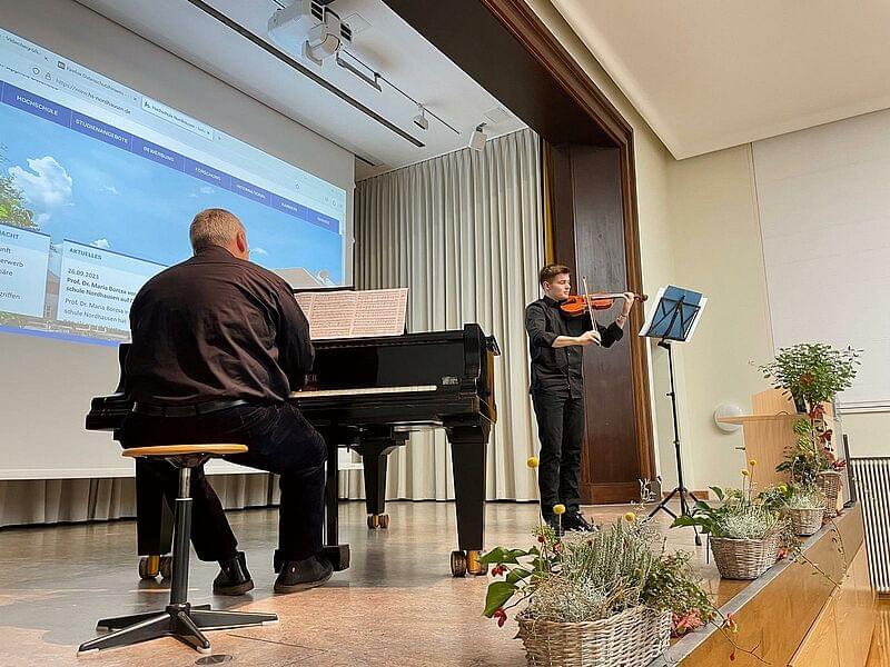a man at the piano and a young man with a violin